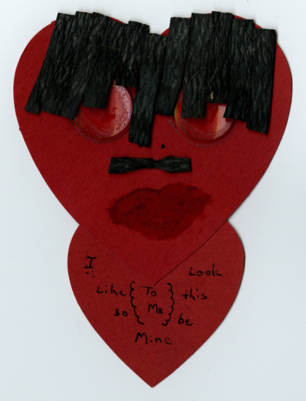 Handmade Valentine that's a funny face on a red paper heart. Inscription says, "To Ma. I look like this so be mine."